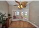 Cozy room with wood floors, dresser, ceiling fan, and double doors leading to a balcony at 3418 Braeside Pl, Clearwater, FL 33759
