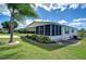 White manufactured home with covered patio and well-manicured lawn at 37608 Lorena Ave, Zephyrhills, FL 33541