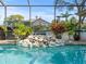 Inviting swimming pool with waterfall feature and screened enclosure at 14173 Pullman Dr, Spring Hill, FL 34609