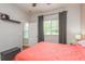 Bright bedroom with coral bedding, window, and door to hallway at 12923 Carlington Ln, Riverview, FL 33579