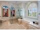 Elegant bathroom featuring a glass shower, a soaking tub, and marble countertops with tile flooring at 3341 Gulf Blvd, Belleair Beach, FL 33786