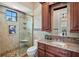 Clean bathroom with a walk-in shower, granite countertop, and wooden cabinets at 3341 Gulf Blvd, Belleair Beach, FL 33786