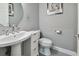Small modern bathroom with pedestal sink, toilet, and round mirror at 348 Larboard Way, Clearwater, FL 33767