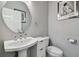 Small modern bathroom with pedestal sink, toilet, and round mirror at 348 Larboard Way, Clearwater, FL 33767