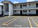 White two-story apartment complex featuring car parking, trimmed shrubs, and balcony access at 304 46Th Avenue W Ter # 218, Bradenton, FL 34207