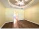 Bedroom showcasing beautiful hardwood floors and a stylish ceiling fan with a tray ceiling at 15810 Cobble Mill Dr, Wimauma, FL 33598