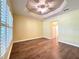 Spacious bedroom featuring dark hardwood floors, ceiling fan, and tray ceiling at 15810 Cobble Mill Dr, Wimauma, FL 33598