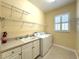 Functional laundry room with washer, sink, and ample shelving for storage at 15810 Cobble Mill Dr, Wimauma, FL 33598