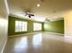 Spacious living room with tiled floor, two ceiling fans, and ample natural light from large windows at 15810 Cobble Mill Dr, Wimauma, FL 33598