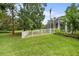 The backyard features lush green grass, a white picket fence, and a screened-in patio at 168 Rue Des Chateaux, Tarpon Springs, FL 34688