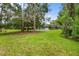 Spacious backyard featuring lush green grass, mature trees, and a screened-in patio at 168 Rue Des Chateaux, Tarpon Springs, FL 34688