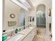Bright bathroom featuring dual sinks, a walk-in shower, a large mirror, and tile floors at 168 Rue Des Chateaux, Tarpon Springs, FL 34688
