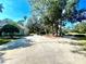 Spacious driveway leading to the home featuring a basketball hoop and mature trees with lush landscaping at 168 Rue Des Chateaux, Tarpon Springs, FL 34688
