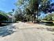 Large driveway featuring a basketball hoop and access to a home surrounded by mature trees and landscaping at 168 Rue Des Chateaux, Tarpon Springs, FL 34688