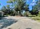 Wide driveway leading to a home with a basketball court, surrounded by lush greenery and pond views at 168 Rue Des Chateaux, Tarpon Springs, FL 34688