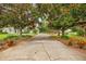 Long driveway leading to a home framed by mature trees and lush landscaping, offering great curb appeal at 168 Rue Des Chateaux, Tarpon Springs, FL 34688