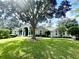 Single-story home with a well-manicured lawn, mature trees, and classic architectural details at 168 Rue Des Chateaux, Tarpon Springs, FL 34688