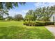 Manicured front yard featuring lush green grass, colorful flowerbeds, and mature trees at 168 Rue Des Chateaux, Tarpon Springs, FL 34688