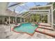 This enclosed pool features an integrated spa, multiple lounge areas, and lush landscaping, creating a private retreat at 168 Rue Des Chateaux, Tarpon Springs, FL 34688