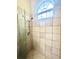 Tiled shower with glass door and window providing natural light creating a bright and functional space at 168 Rue Des Chateaux, Tarpon Springs, FL 34688