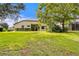 Large backyard with lush green grass, mature trees, and a screened enclosure at 3320 Majestic View Dr, Lutz, FL 33558