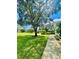 Landscaped front yard with mature tree and walkway leading to home entrance at 168 Rue Des Chateaux, Tarpon Springs, FL 34688