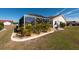 Backyard with a screened-in lanai, surrounded by tropical landscaping at 701 Westmont Way, Sun City Center, FL 33573