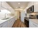 Modern kitchen with white cabinets, stainless steel appliances, quartz countertops, and wooden floors at 701 Westmont Way, Sun City Center, FL 33573