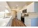 Well-lit kitchen featuring white cabinets, quartz countertops, stainless steel appliances, and wood flooring at 701 Westmont Way, Sun City Center, FL 33573