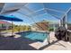 Screened-in pool area with a blue umbrella, patio, and lush green landscaping at 701 Westmont Way, Sun City Center, FL 33573