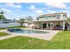 Backyard pool featuring a covered patio with comfortable seating and dining areas overlooking the lush, green lawn at 7886 9Th S Ave, St Petersburg, FL 33707