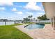 Inviting swimming pool with a tile waterfall feature, lush landscaping, and a picturesque waterfront backdrop at 7886 9Th S Ave, St Petersburg, FL 33707