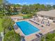 Aerial view of a community pool with an abundance of lounge seating in a fenced outdoor area at 1662 Seascape Cir # 205, Tarpon Springs, FL 34689