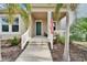 Inviting front entrance featuring a landscaped yard, a charming porch, and an American flag at 707 Winterside Dr, Apollo Beach, FL 33572