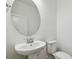 A pedestal sink and toilet are in a light and bright bathroom with a round mirror at 6681 Michael Favor Way, Wesley Chapel, FL 33545