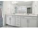 Bright bathroom features double sink vanity with white cabinets, stone countertop and a large mirror at 6681 Michael Favor Way, Wesley Chapel, FL 33545