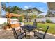 Landscaped backyard with hot tub under pergola and patio with seating under a large umbrella at 1667 Suffolk Dr, Clearwater, FL 33756