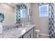 Bathroom with granite countertop, gray cabinets, and patterned curtains at 18357 Cropside Trl, Bradenton, FL 34211