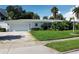 A white single-story house with a gravel driveway, lush lawn, and mature landscaping at 15301 Harbor Dr, Madeira Beach, FL 33708