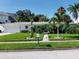 White single-story home with a spacious lawn, palm trees, and a two-car garage at 15301 Harbor Dr, Madeira Beach, FL 33708