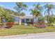 Inviting single story home with lush landscaping including mature palms and a welcoming entrance, near the street at 165 4Th N Ave, Tierra Verde, FL 33715