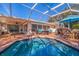 Stunning screened-in pool area with comfortable seating, outdoor grill, and clear blue water at 165 4Th N Ave, Tierra Verde, FL 33715