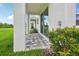 Charming back patio with stone pavers, white columns, lush grass, and flourishing shrubbery at 31895 Anchor Point Dr, Wesley Chapel, FL 33545