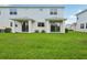 Back of townhome displaying lush green grass and sliding glass doors that lead to covered patio areas at 31895 Anchor Point Dr, Wesley Chapel, FL 33545
