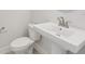 Clean white half bath with a pedestal sink, modern faucet, and a matching toilet for guests at 31895 Anchor Point Dr, Wesley Chapel, FL 33545