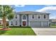 Two-story house with gray siding, red door, and three-car garage at 8378 Gibralter St, Spring Hill, FL 34608
