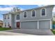 Two-story house with gray siding, red door, and three-car garage at 8378 Gibralter St, Spring Hill, FL 34608