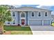 Two-story house with gray siding, red door, and three-car garage at 8378 Gibralter St, Spring Hill, FL 34608