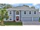 Two-story house with gray siding, three-car garage, and red front door at 8378 Gibralter St, Spring Hill, FL 34608