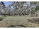 Open grassy backyard with mature trees and a rustic fence at 1106 Oxbow Rd, Wimauma, FL 33598